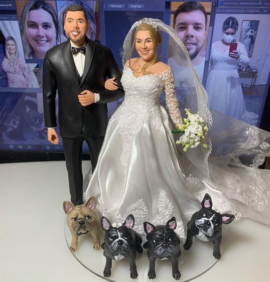Esculturas de casal de noivos com vestido branco e smoking preto, cercados por esculturas de bulldogs franceses